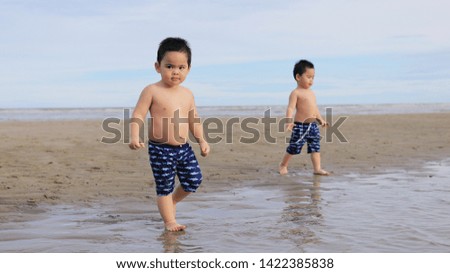 little twin boys walking on the beach