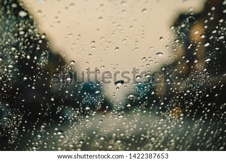 Drops Of Rain On Blue Glass Background. Street Bokeh Lights Out Of Focus. Autumn Abstract Backdrop.