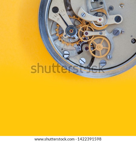 Mechanic clockwork mechanism, spring bronze cogs wheels macro view. Shallow depth of field, selective focus. Yellow colorful background. Copy space.