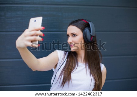 Self portrait of pretty positive girl shooting selfie on front camera with two hands isolated on dark background. Joy fun concept - Stock image