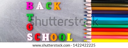 The layout of school supplies on a dark gray background. Top view, the sun's rays from the side. Flat lay. Back to school.