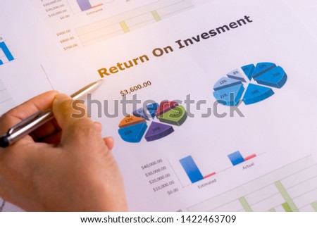 Close-up of businessman hand holding a paper document of financial report of Return on Investment, ROI. Analysing on investment risk management. Business Plan concept.