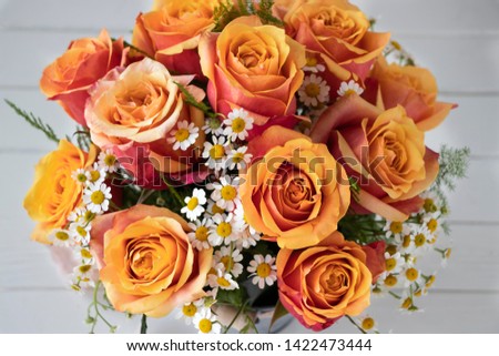 Bouquet of orange roses with white wood background.