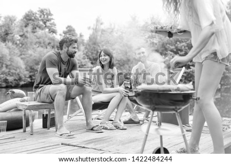 Black and White photo of 
Low section of woman preparing food in barbecue grill with friends on pier