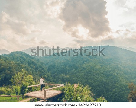 travel in tropical forest and camping, adventure vacations concept from man photographer is taking picture of sunset mountains landscape with happiness and freshness.