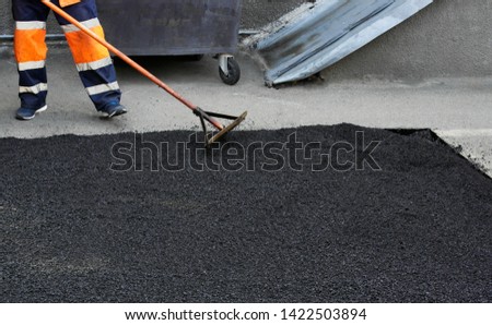   Laying asphalt, covering the pit, on the rubble. Workers carry in shovels, hot asphalt.closeup photo.