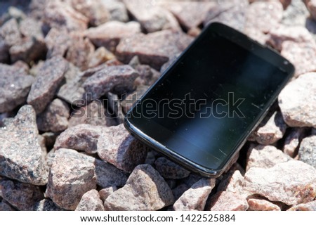 Broken cellphone abandoned and lost among the gravel.
