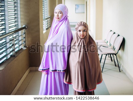 portrait muslim mother and daughter isolated over home background