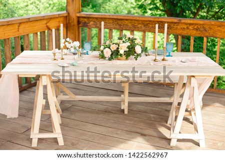 Decorated table for dinner for two person, with plates knife, fork, cheese, wine, wine glasses and flowers in a copper vase.