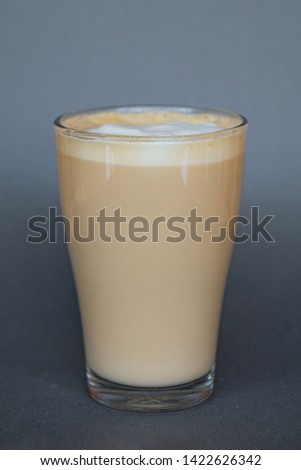 large transparent glass filled with cold summer drink coffee with milk photographed on the isolated gray background picture for the menu