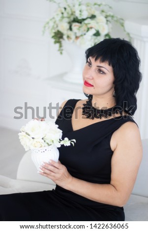 Young woman in a bright room. Woman in a black dress. Beautiful young woman.
