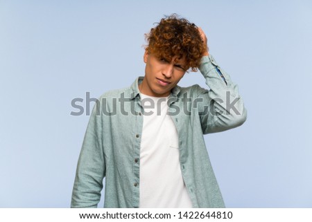 Young african american man over isolated blue wall with an expression of frustration and not understanding