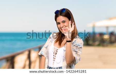 Young woman in bikini in summer holidays showing ok sign with fingers at the beach
