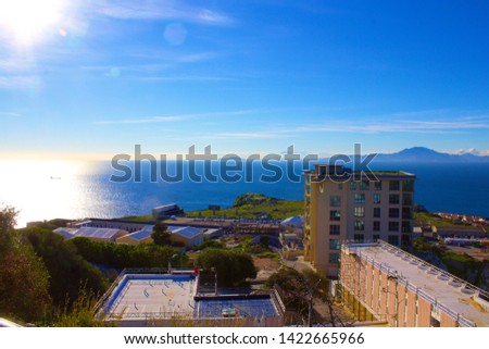 View across the straight of Gibraltar to North Africa from the Rock of Gibraltar across the building tops down to the ships at anchor to the mountains in the distance on a clear sunny day Royalty-Free Stock Photo #1422665966
