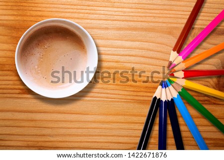 Hot coffee mug and colour pencils on striped wooden desk
