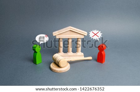 Two figures of people opponents stand near the courthouse and the judge's gavel. Conflict resolution in court, claimant and respondent. Court case. the defendant defends the position of innocence. Royalty-Free Stock Photo #1422676352