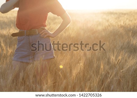 happy young girl joys at the wheat field at the evening time. sunset and atmospheric mood
