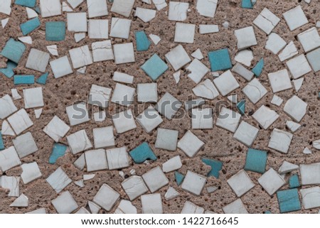Concrete surface with splashes of many small multicolored tiles.