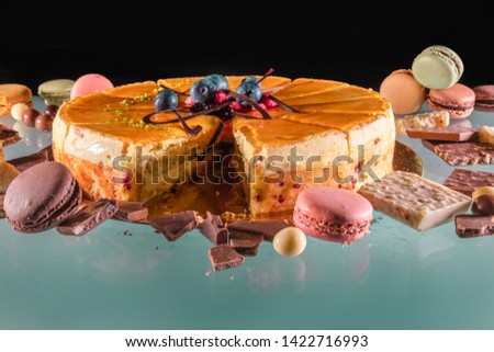Delicious celebration cake decorated with berries and strawberries, accompanied by macaroons and chocolate candies with a black background