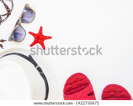 Top view flat lay of hat, red starfish, sunglasses, red flip flops isolated on white background.
