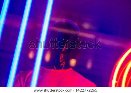 Black mannequin on a shop window in a white t-shirt. Neon lighting, blue and purple. Stylish young man
