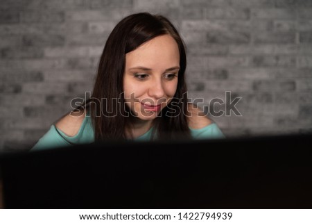 Young woman using laptop computer sitting in front of white brick wall background, people and technology, lifestyles, education, business concept