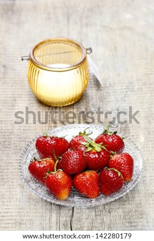Strawberries and single orange candle on rustic wooden table. Copy space, selective focus.