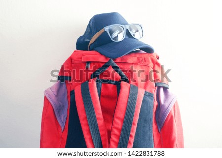 Blue cap and sunglasses on red backpack