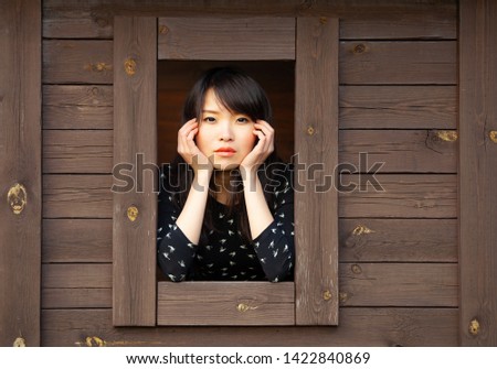 Pretty Asian girl portrait in wooden hut. Expressive portrait of lonely woman.