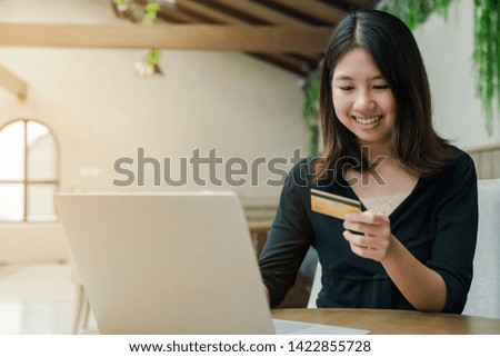 Closeup Asian beautiful woman Wearing a black shirt Sitting in the house Have a credit card in hand Is buying online products with a laptop computer.