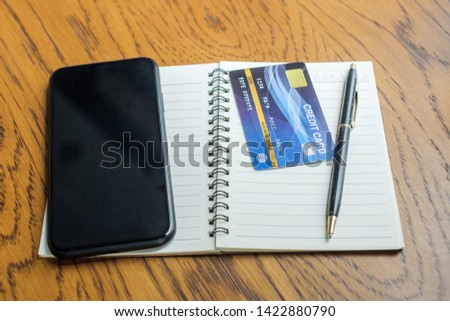 notebook, credit card and touchscreen smartphone on table. business, lifestyle, technology, ecommerce and online payment concept