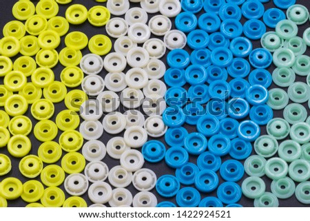 Many tiny colored round plastic buckles stitched into an abstract colorful background