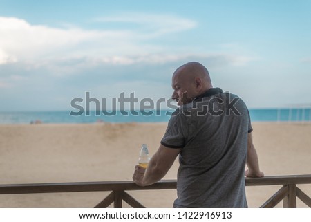 man drinking beer by the sea