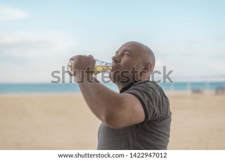 man drinking beer by the sea