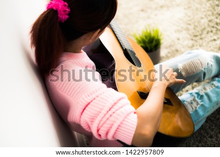 A beautiful asian woman playing acoustic guitar