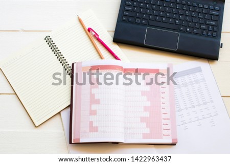 notebook account planner ,computer and financial statement for business work arrangement flat lay style on background white at office 