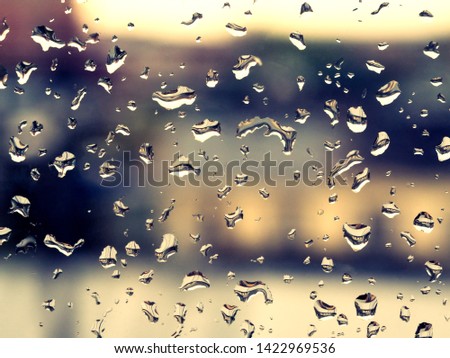 Rainy drops on the glass with the dark blue blurry background