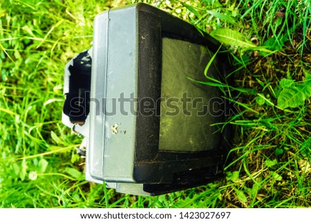 Old retro TV in the grass.Garbage on the planet. Contamination of the natural environment. Recover forgotten, device, out of place. Someone forgot his television on the field.