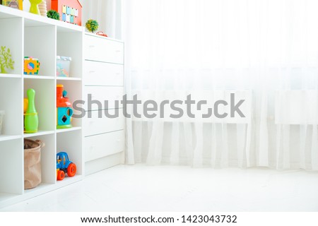 Copy the space of an empty wall in a simple children's room with a white wooden floor and a large and light window. Background Royalty-Free Stock Photo #1423043732