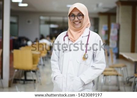 Hijab  doctor standing at library and smiling