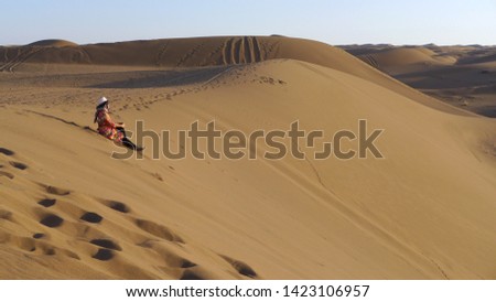 A female tourist posing for a picture on a large sand dune near Kashan, Iran.