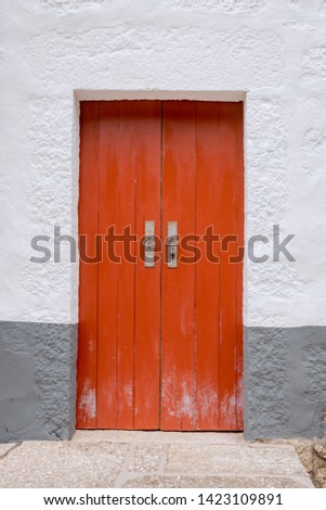 Old red door in a stone building painted white and gray. Background