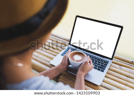 Women hand holding a hot espresso mug Put on a laptop mockup on a bamboo table, outdoor