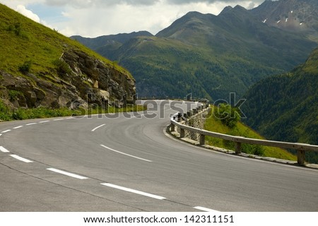 Road turning in the mountains Royalty-Free Stock Photo #142311151