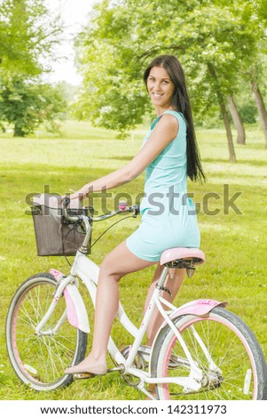 Young woman ride bicycle in the park at beautiful spring day.