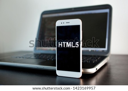 Mobile application development, HTML5 programming language for mobile development. Workplace of programmer, tester, laptop, and smartphone