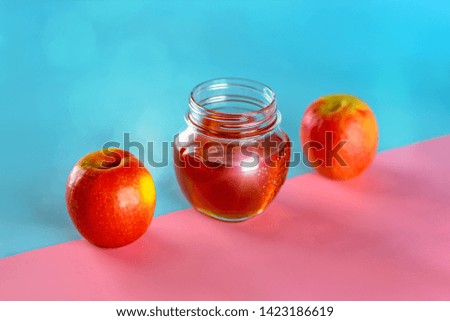 Rosh hashanah jewish holiday concept. Apples and honey jar for jewish new year holiday over blue pink background. Healthy food.Bokeh lights.