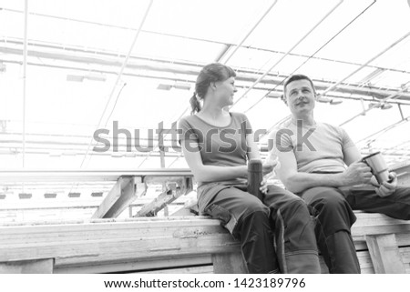 Black and White photo of Smiling botanists sitting with coffee in greenhouse