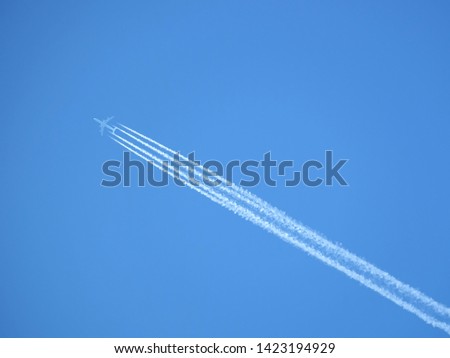 Big passenger supersonic airplane with four jet engines flying high in clear cloudless blue sky, leaving long white trace Royalty-Free Stock Photo #1423194929