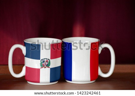 France and Dominican Republic flag on two cups with blurry background